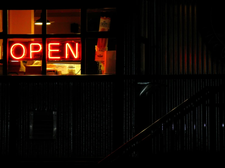 a building with a open window lit by a neon sign