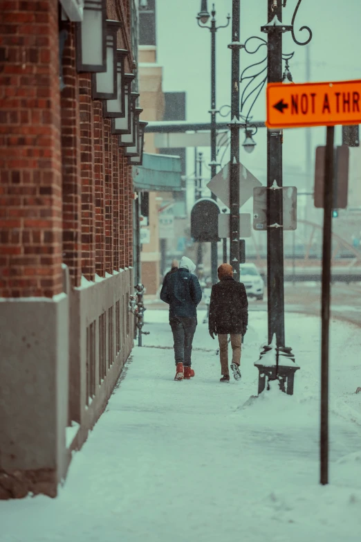 two people walking down the street in the snow