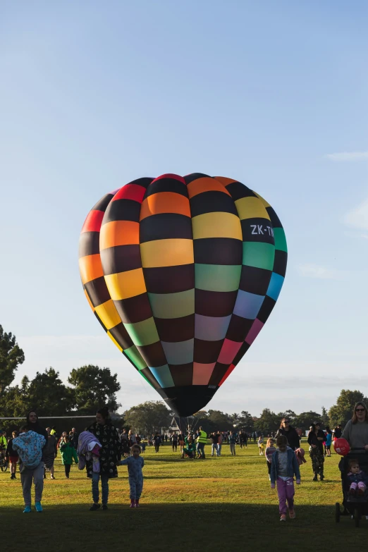 many people standing in the grass flying a large kite