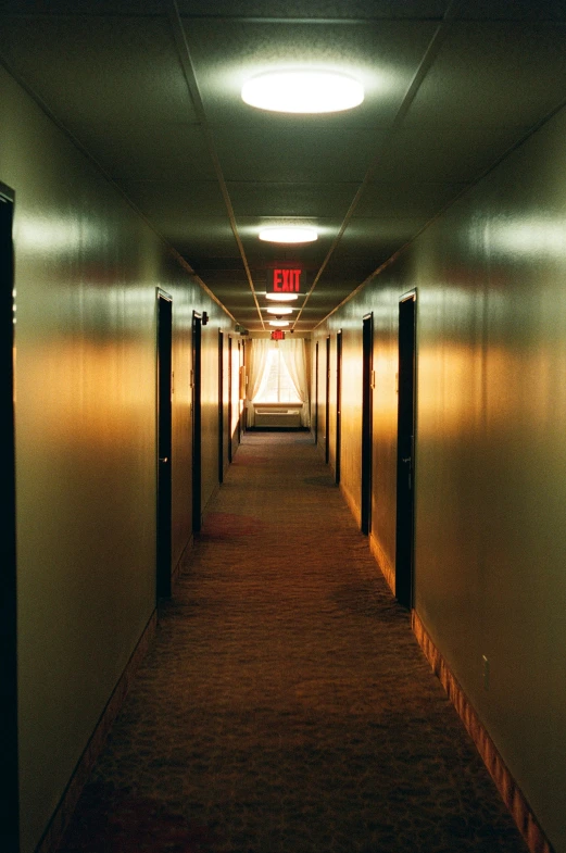 long white hallway with multiple doors and a red light hanging from the ceiling