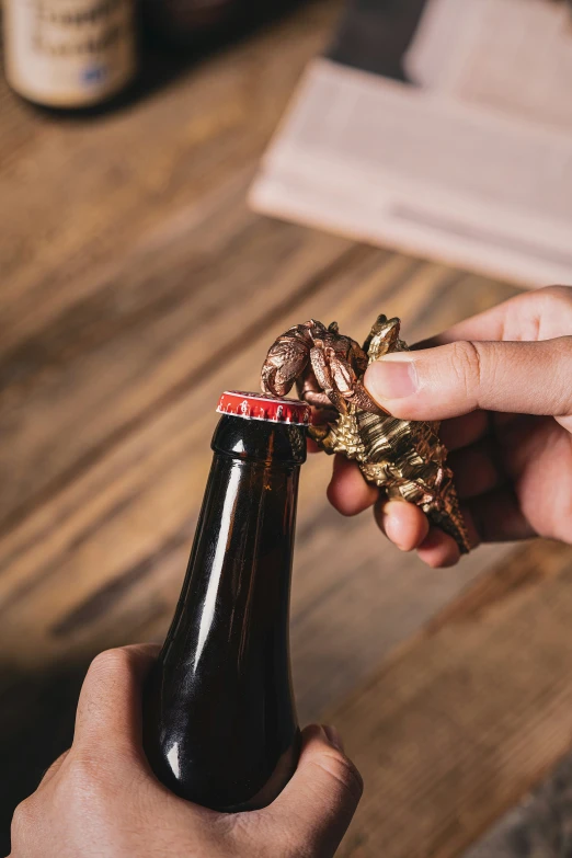 a person holds a bottle opener and gold bird charm