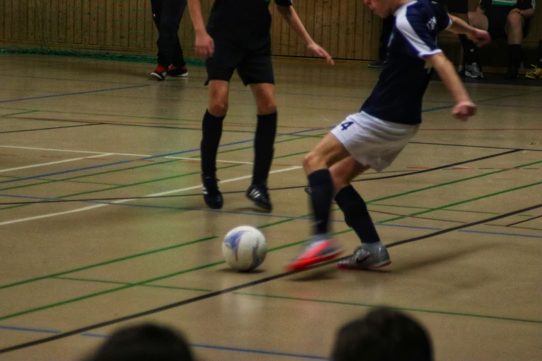 two soccer players chasing after the ball as an audience watches