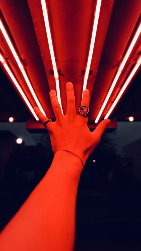 a hand with an elegant ring is posed in front of red lights