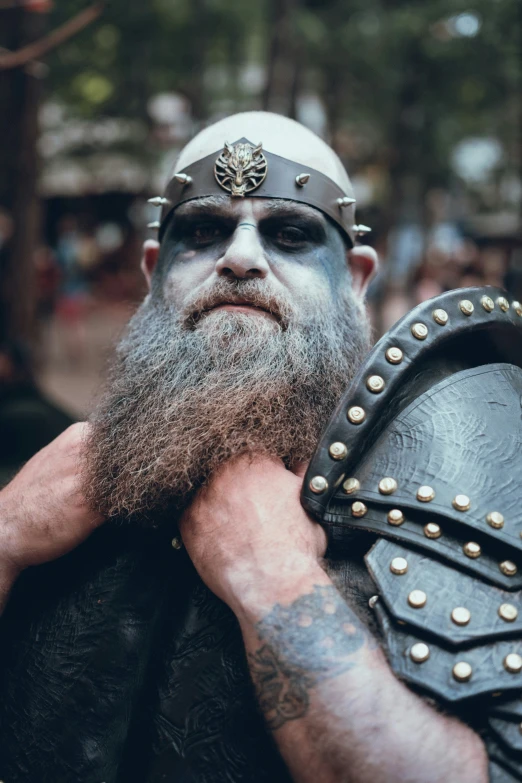 a bearded viking holding a shield while looking off to the side