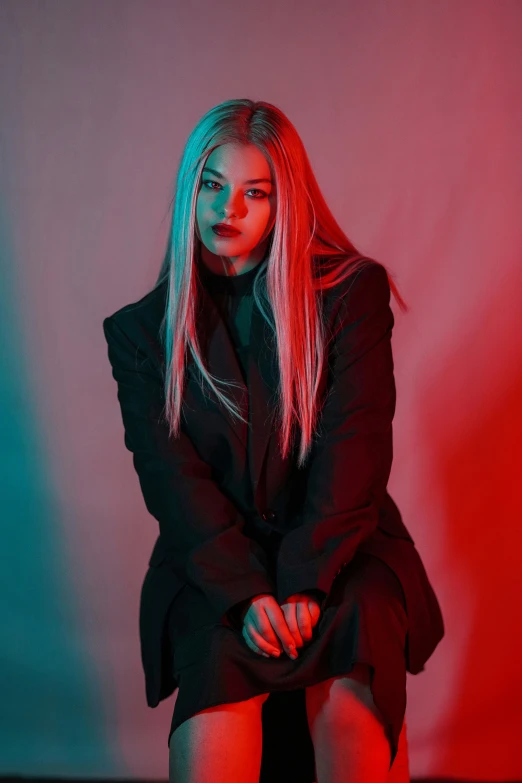 a woman sitting on a stool and looking at the camera