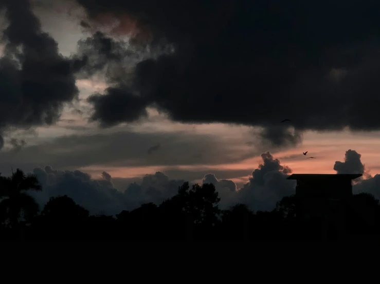 the sky is full of dark clouds and some trees