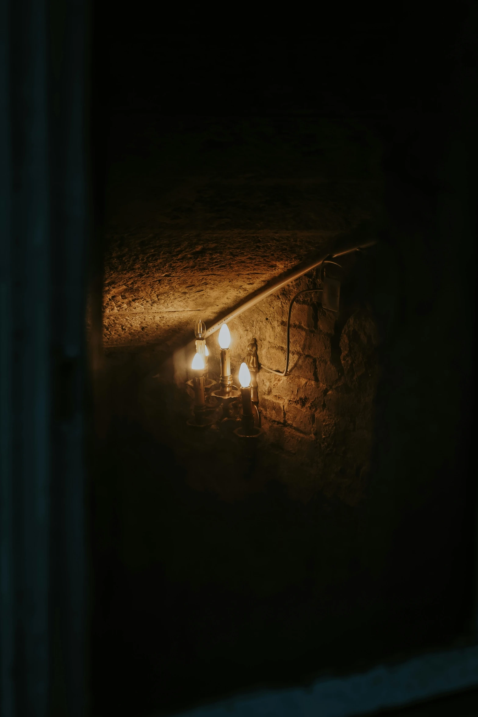 three candle lit candle light in a stone wall