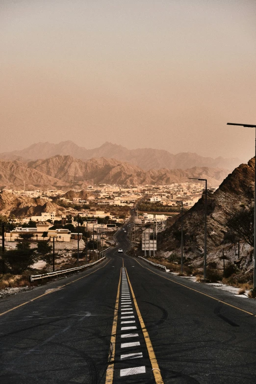 the view down an empty highway with mountains in the background