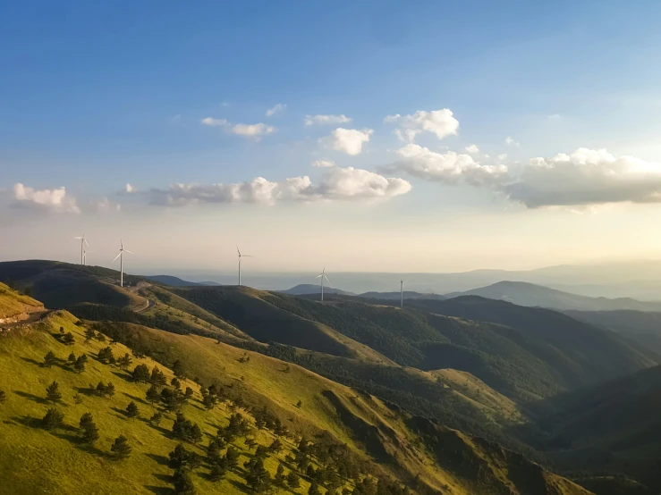 a large hill with green hills and windmills on the top