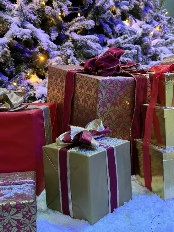 several wrapped presents sit in front of a tree with christmas decorations