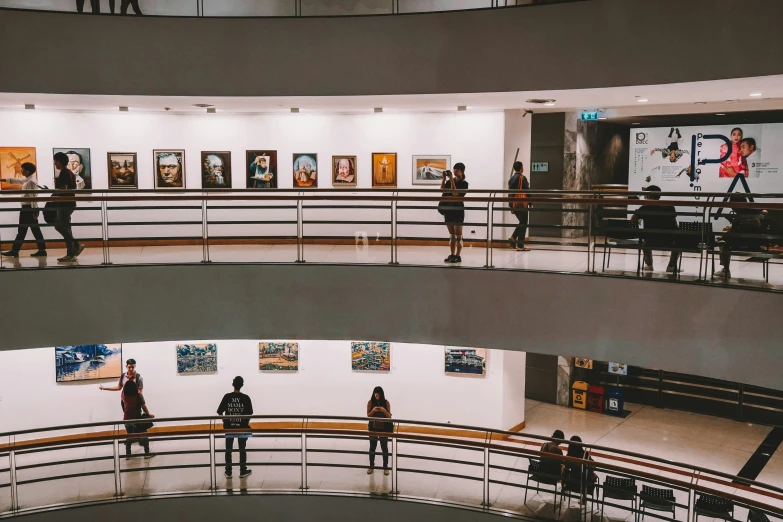 three views of people walking past a display of paintings