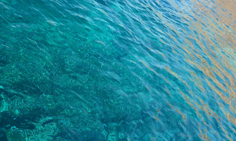 an ocean with orange and yellow sand and blue water