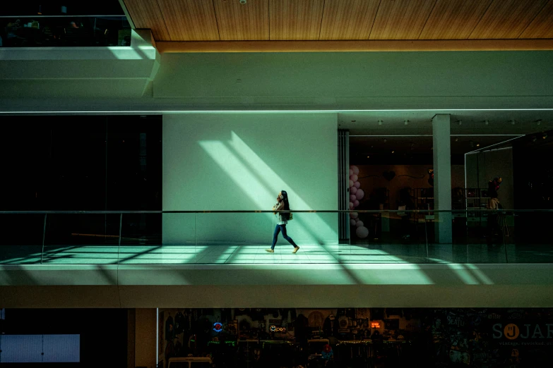 a woman in a jacket and jeans is walking in an indoor hallway