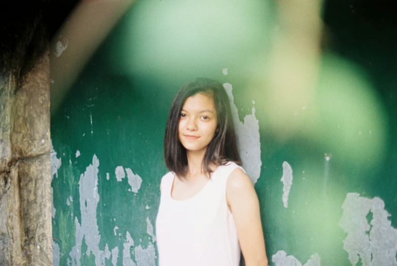 a girl in a white shirt standing by a wall