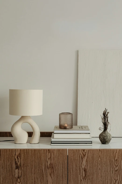 a white lampshade on a wooden desk next to books