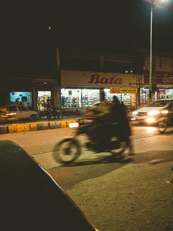 a man riding a motorcycle at night down a city street