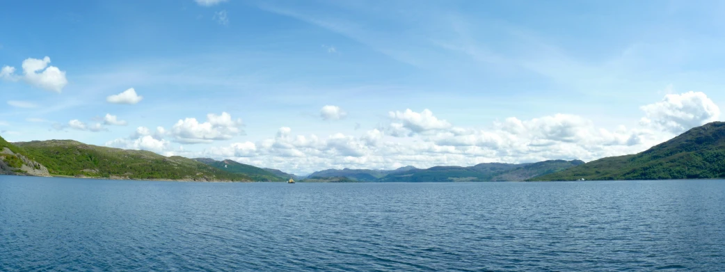 lake surrounded by hills with clouds in the sky