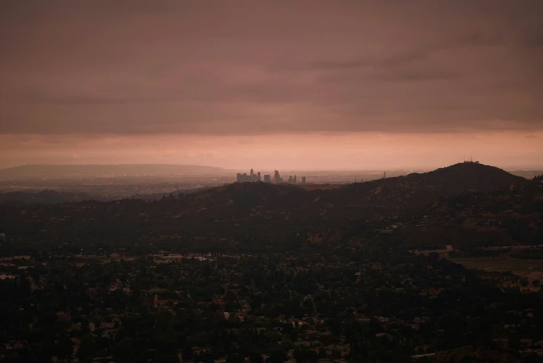 a cloudy view of a mountain and the city in the distance