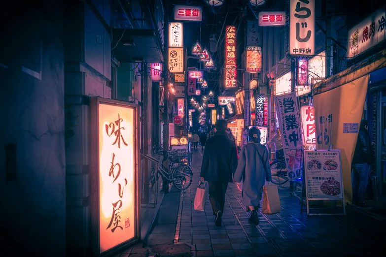 the people are walking in the alley where business signs are hanging