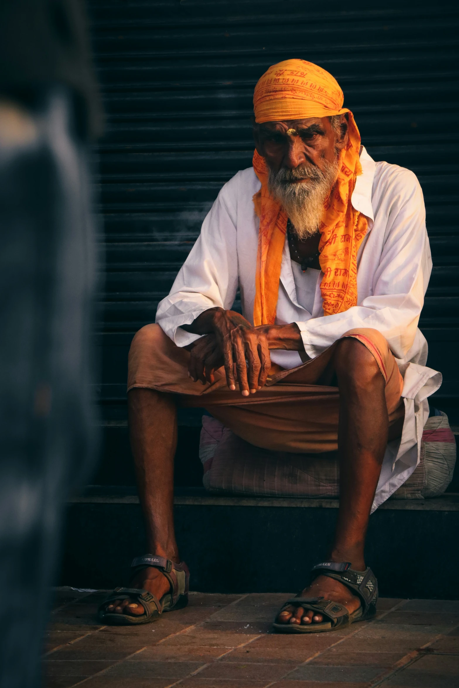 a man sits on a step while wearing an orange hat