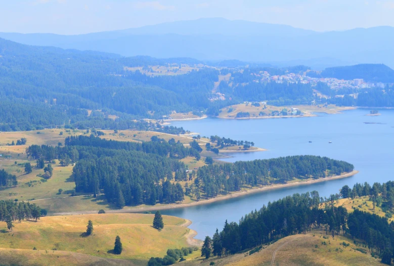 a lake and field in the middle of mountains with blue sky