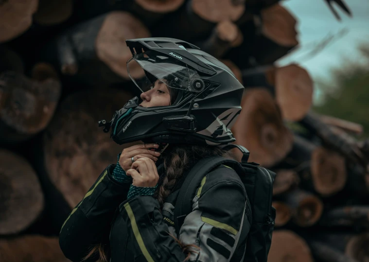 the young woman is wearing her helmet and walking beside logs