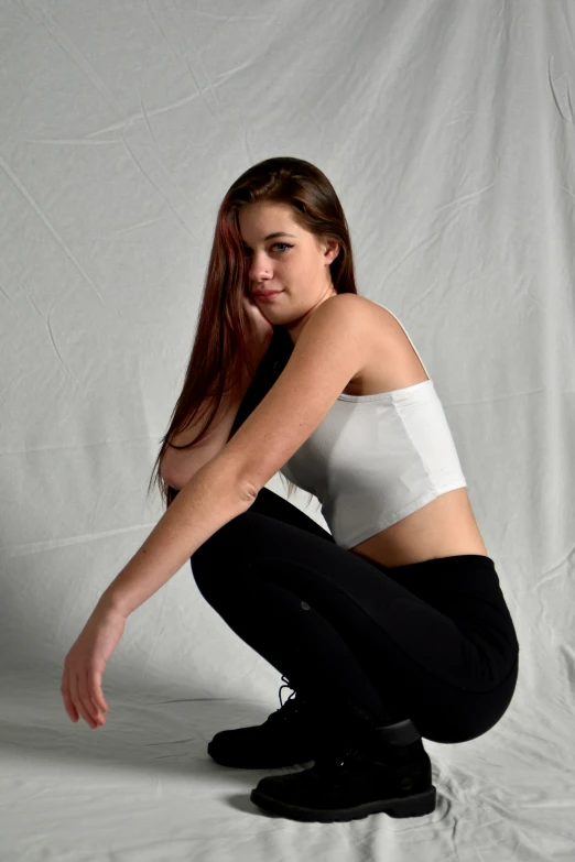 young lady in white sports  and black pants posing