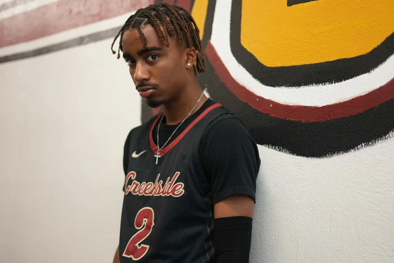 a boy wearing a black basketball jersey standing in front of a painting