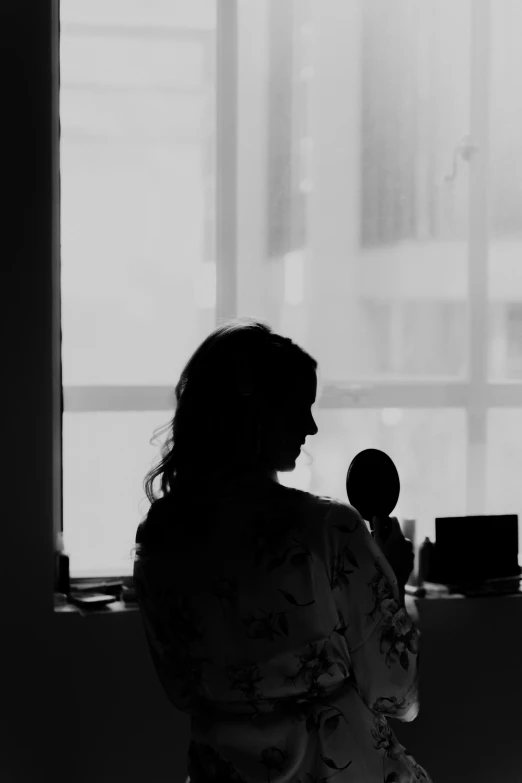 the silhouette of a woman in front of a window