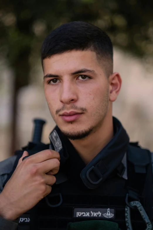 a young man with a goatee is holding onto his police uniform