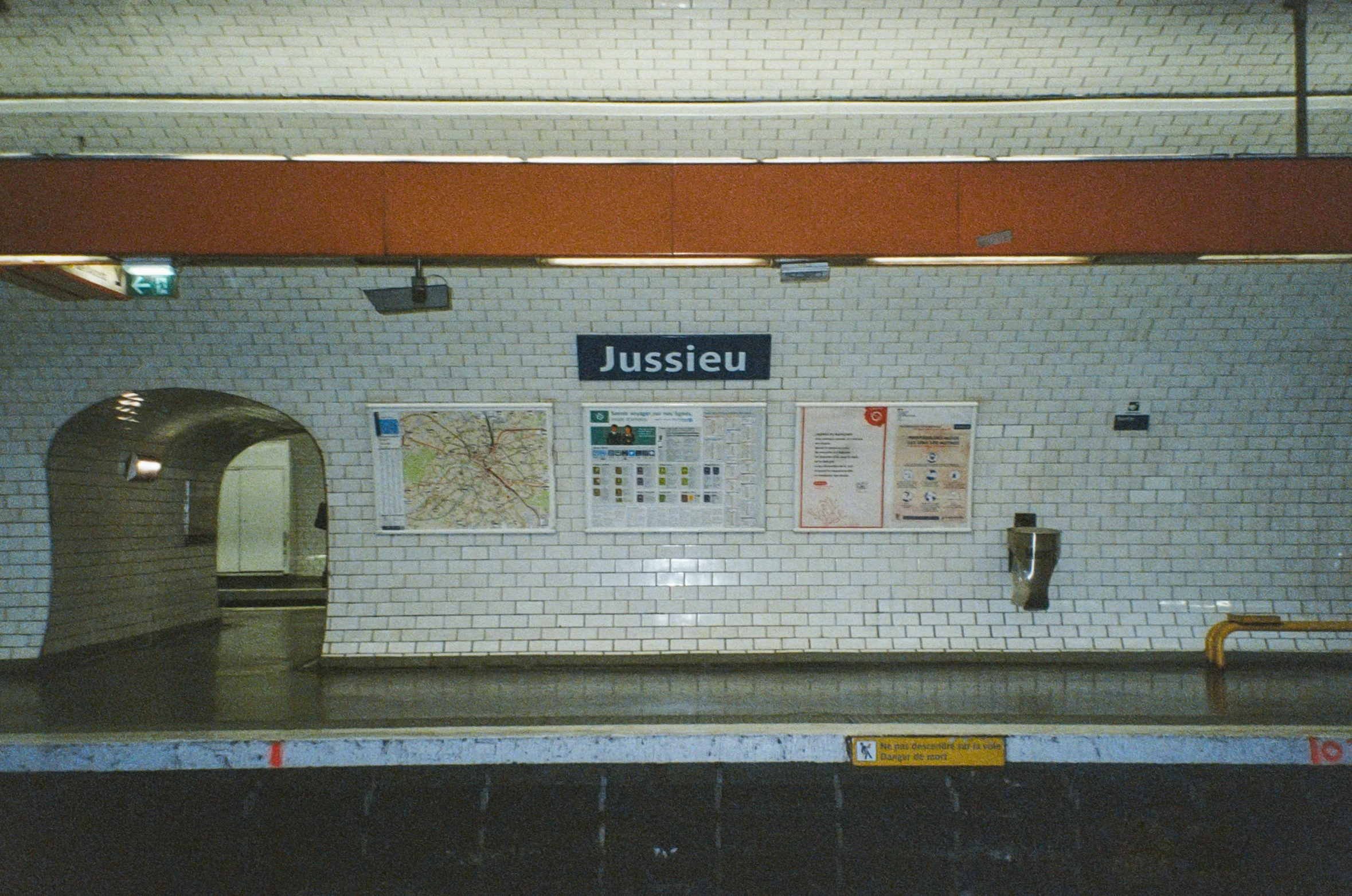 a subway with a white brick wall and red beams