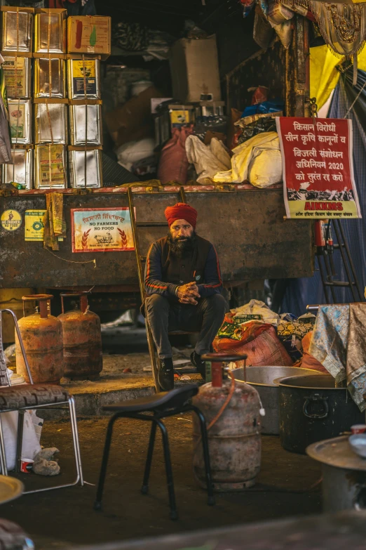 a man in an indian bazaar sitting next to various items