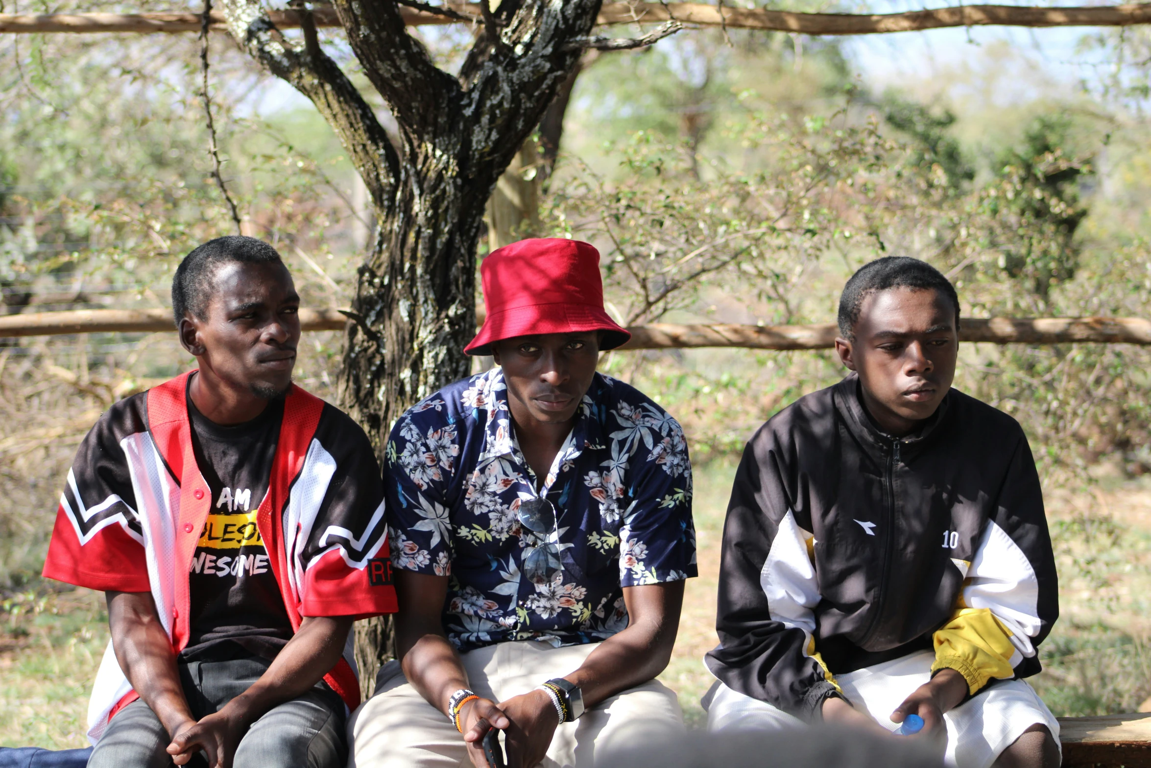 three men sitting on a bench with red hats