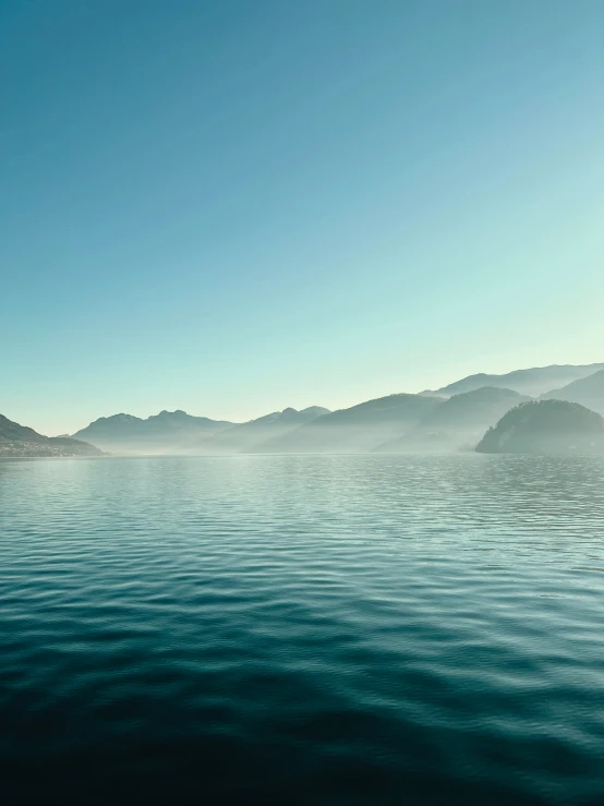 the water is calm with mountains in the background