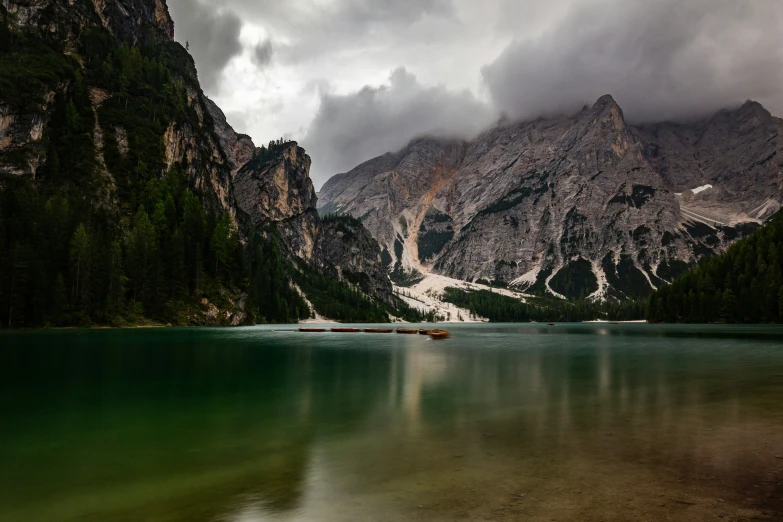 a body of water next to a mountain range under a cloudy sky