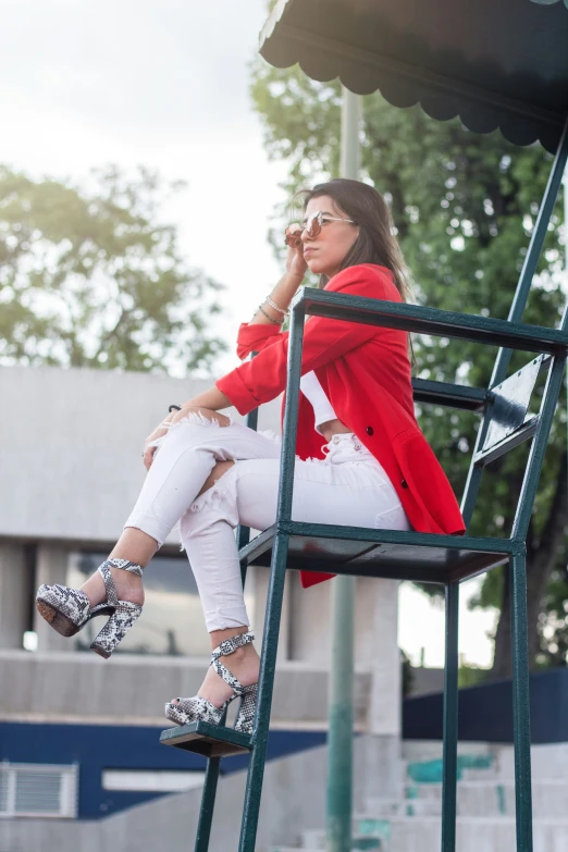 a woman sitting in a metal chair talking on a cell phone