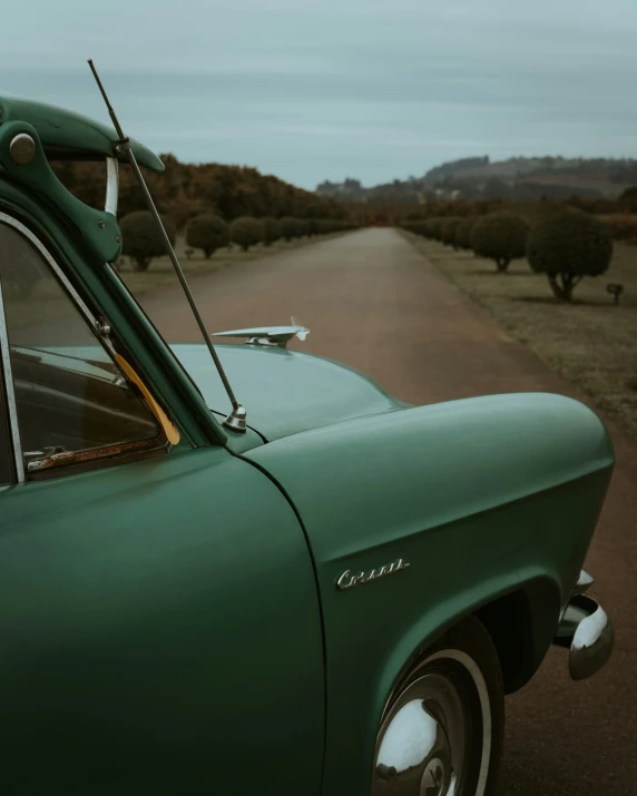 a small green classic car on an old road