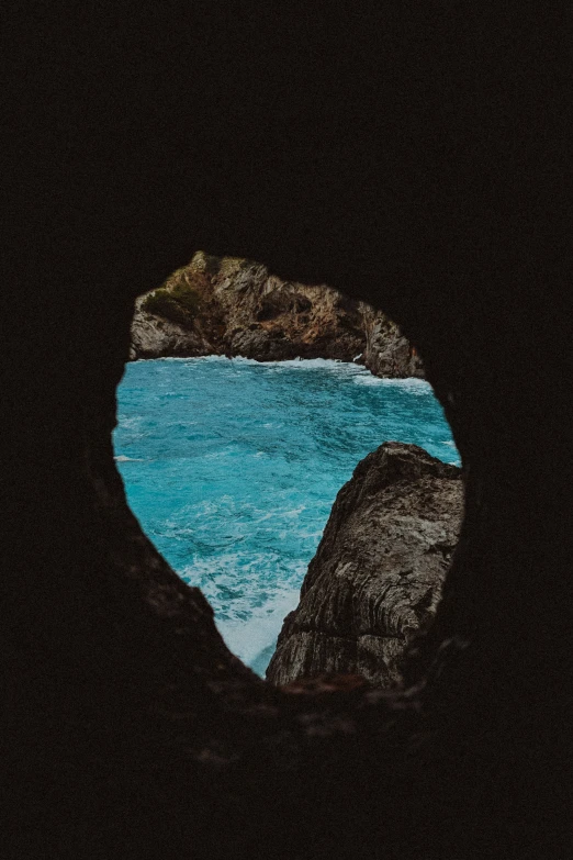 a view of an ocean through the hole of some rock