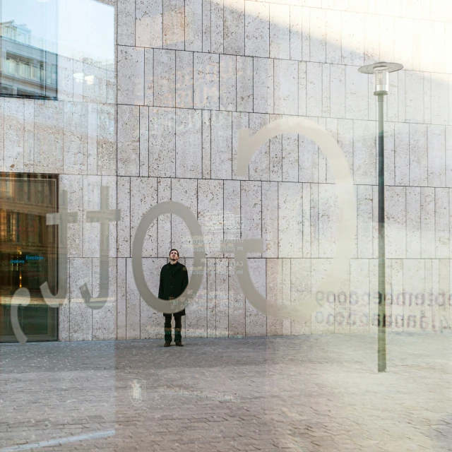 person wearing black walking on sidewalk past wall