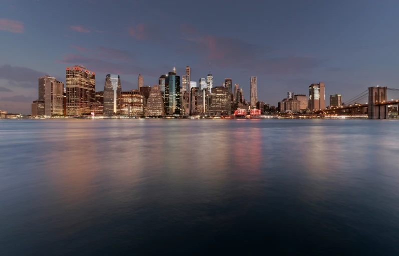 a city skyline over water as the sun goes down