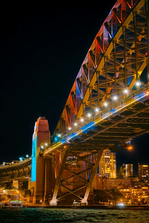 a city with buildings and lights underneath the bridge