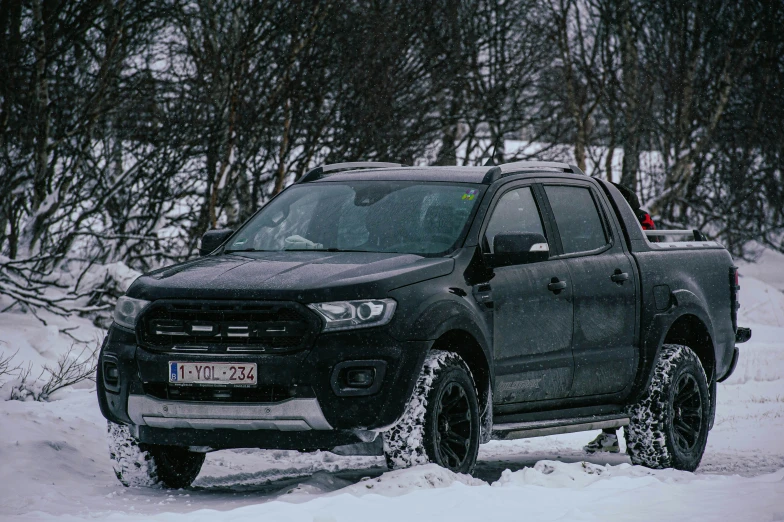 a black pick up truck driving through some snow