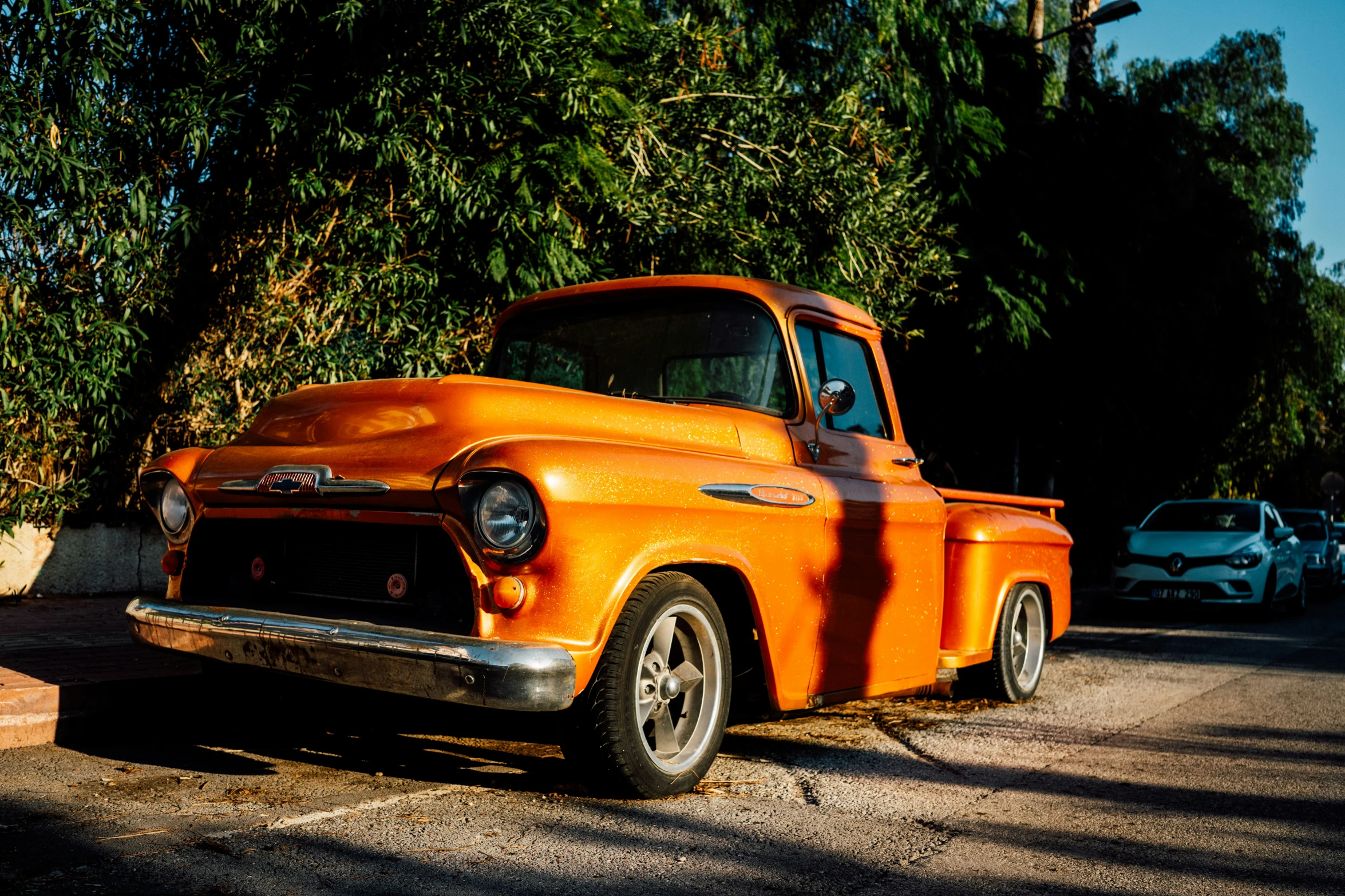 an orange pick up truck parked on the side of a street