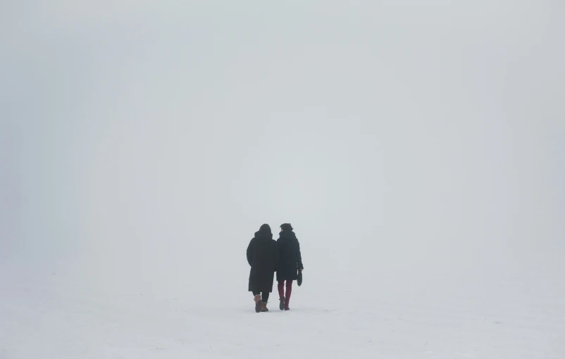 two people walking in snow with one on her back