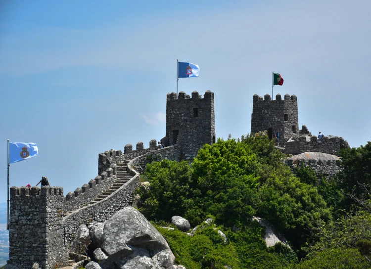 a castle wall and flags near the ocean