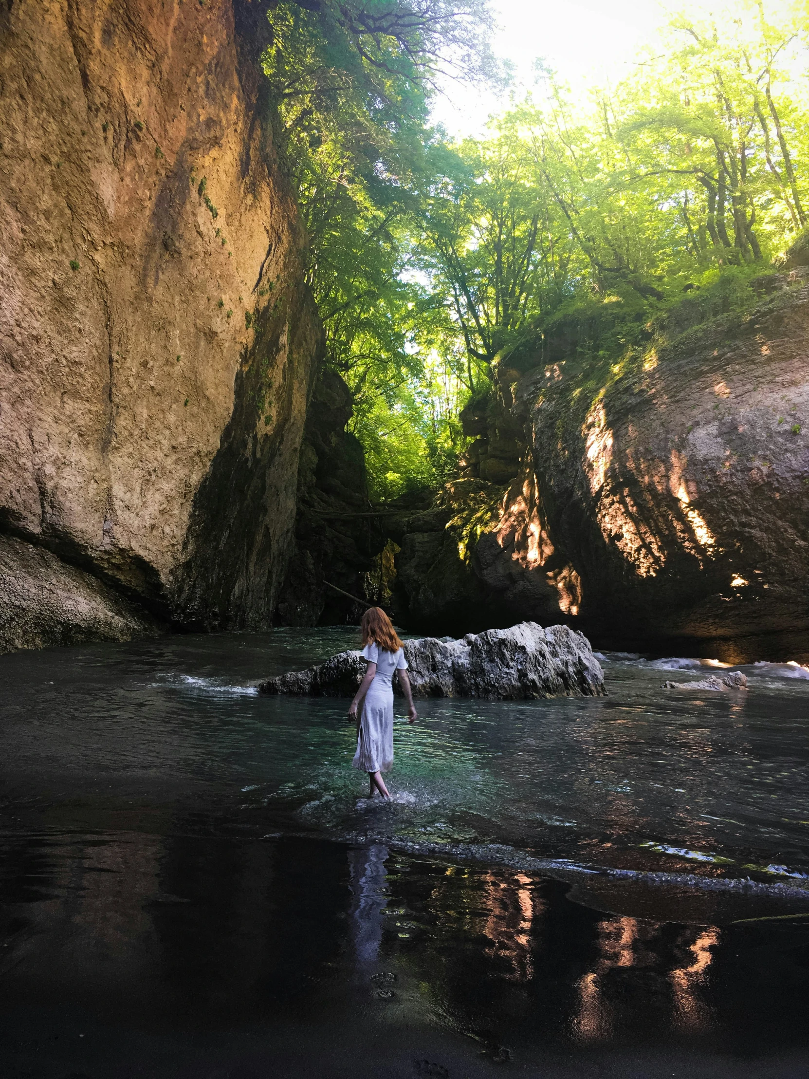 girl walking on the edge of a pool near a huge cliff