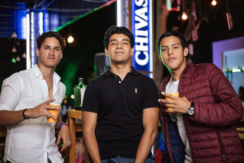 three men standing next to each other holding drinks