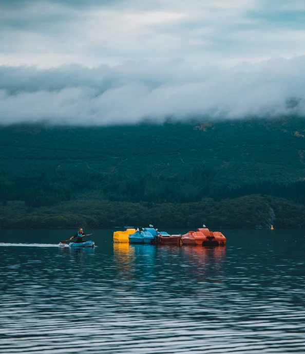 some small boats floating in the water on a cloudy day