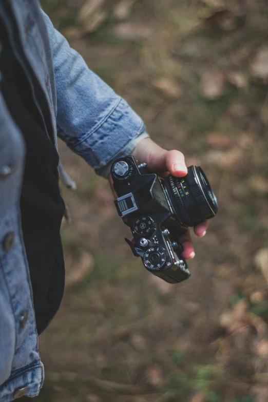 a person holding an old fashioned camera with a blurred background