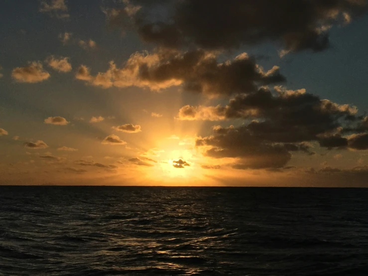 the sun set on an ocean with a very nice cloud